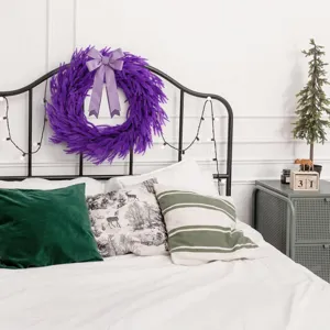 Paarse Norfolk dennen kerstkrans met lavendel strik op een hoofdeinde.