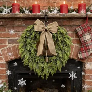 Belle couronne de Noël verte avec nœud en toile et cloches sur une cheminée en brique