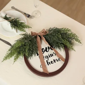 Macro view of artificial cedar branch decor with ribbon and Love Begins at Home text