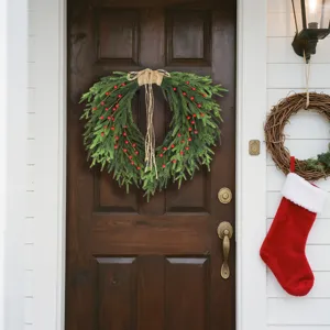 Artificial Norfolk pine wreath with red berries hanging on a dark wooden front door