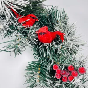 Detailed macro view of red cardinal birds on flocked pine needles with red berries