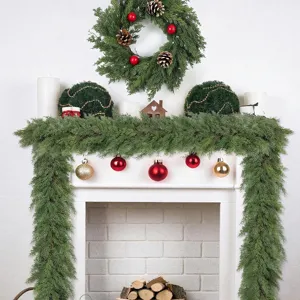 Guirnalda y corona de cedro navideño con adornos rojos y dorados en chimenea blanca.