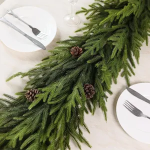 Close-up of realistic PE Norfolk pine garland with pine cones on festive dinner table