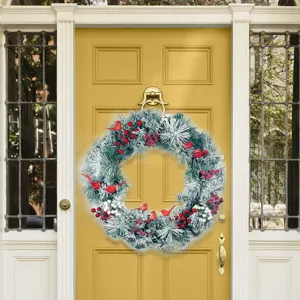 Artificial Christmas wreath with red cardinal birds and berries on a yellow front door