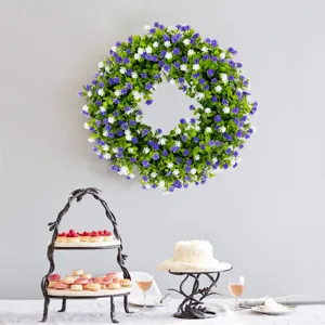 Lush eucalyptus wreath with purple and white flowers hanging on a wall above a dessert table
