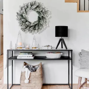 Close-up of flocked Christmas wreath hanging on a minimalist white living room wall