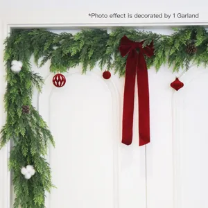 Detailed view of a realistic Norfolk pine garland with a red bow on a white door.