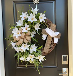 Detailed macro view of an Easter wreath featuring white lilies and a rustic wooden cross