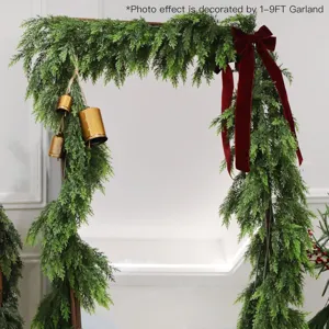 Detailed view of realistic Norfolk pine garland with red bow and gold bells.