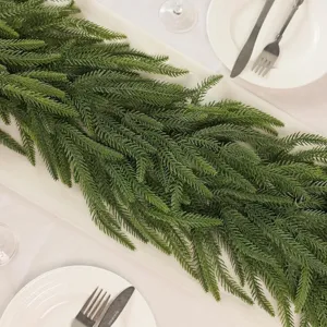 Detailed close-up of a lifelike PE Norfolk pine garland on a white holiday dining table setting