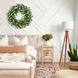 Purple and white babysbreath wreath hanging on a white wall in a cozy bedroom