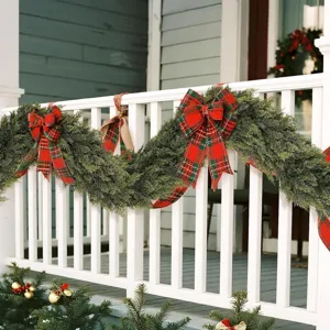 Artificial Norfolk pine Christmas garland with red plaid bows on white porch railing