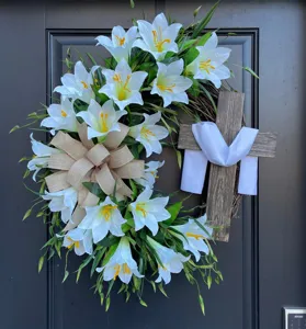 Macro view of Easter wreath featuring white lilies, burlap bow, and a wooden cross
