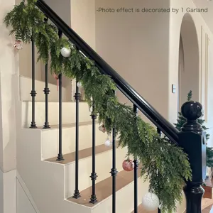 Detailed view of a lush faux Norfolk pine garland draped on a black staircase railing.