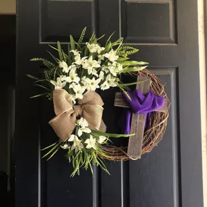 Close-up of Easter wreath with white lilies, burlap bow and purple draped cross