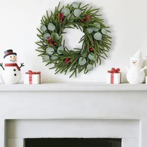 Realistic artificial Christmas wreath with cypress, eucalyptus leaves, and berries above fireplace