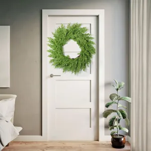Una ghirlanda di Natale da 20 pollici con aghi di pino verde su una porta bianca