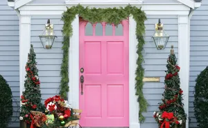 Guirlande de cyprès artificiel réaliste drapée sur une porte d'entrée rose vif.