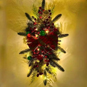 Festive illuminated Christmas stair swag decorated with red berries and plaid bow