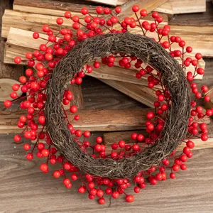 Detailed view of a festive red berry Christmas wreath on rustic wood logs background.