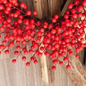 Detail shot of a vibrant red berry Christmas wreath on a rustic wood background