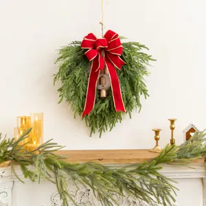 Close-up detail of a lush green Christmas wreath with large red velvet bow and copper bells