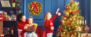 Christmas PVC wreath with red bow and LED lights hanging on wall in festive room.