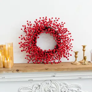 Red berry Christmas wreath displayed on a rustic wooden mantel with gold decor.