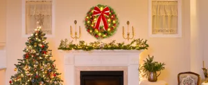 Festive Christmas wreath with red bow and warm lights hanging above a classic white fireplace
