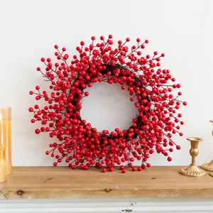 Festive red berry Christmas wreath displayed on a rustic wooden mantle wall decoration.