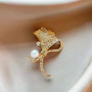 Elegant gold ginkgo leaf brooch detail, shining rhinestones and white pearl embellishment.