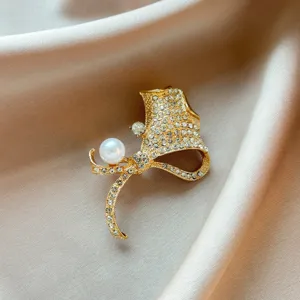 Detailed shot of an elegant gold-toned pearl rhinestone brooch, showcasing sparkling crystal details.