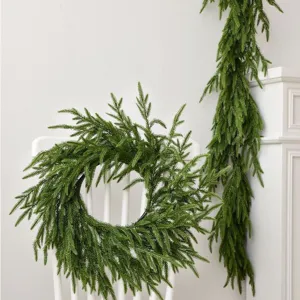 Lush Norfolk Pine Christmas wreath and garland displayed on a white chair and mantle