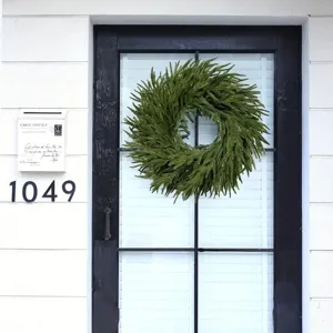 Green artificial fern wreath hanging on a minimalist black and white front door.