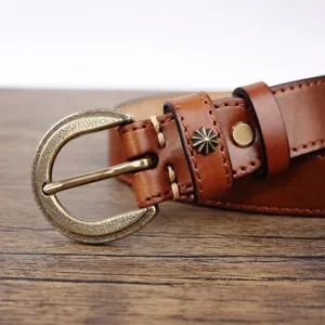 Close-up detail of vintage genuine leather belt with antique brass buckle and rivet.