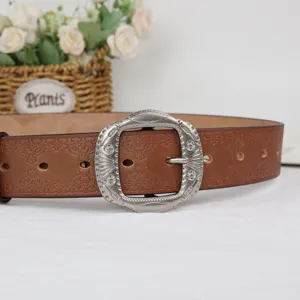 Close-up detail of retro embossed brown leather belt with ornate carved silver buckle.