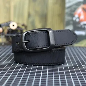 Closeup of black genuine cowhide leather belt with dark metal pin buckle and fine stitching.