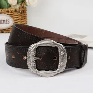 Detailed shot of vintage brown leather belt with ornate silver metal buckle for women.