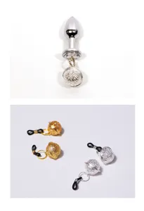 Detailed shot of palace bell adult novelty clamps and metal plug with hollow carved design.