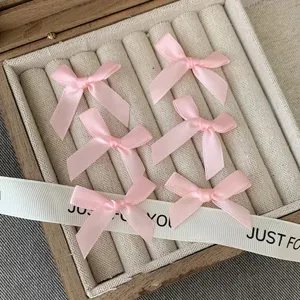 Detail shot of pink satin bow knots neatly arranged in a storage box for DIY hair accessories.
