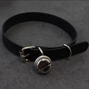 Closeup of black leather choker collar with metal bell detail, punk harajuku style accessory.
