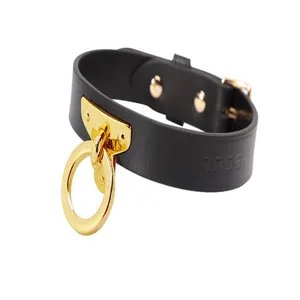 Close-up detail of black leather choker necklace with shiny gold O-ring and hardware.
