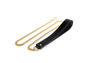Detailed shot of black leather choker necklace with gold chain and metal clasp ornament.