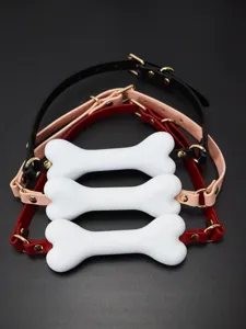 Vue détaillée de bâillons en os silicone avec lanières en cuir réglables et attaches dorées.