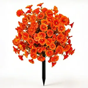 Close-up of vibrant orange artificial petunias with a black garden ground stake