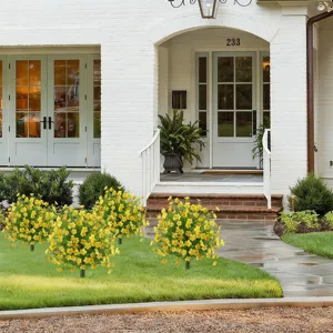 Artificial yellow flower stakes for outdoor garden decor in front of a white house.