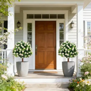 Pair of artificial daisy topiary trees in grey pots on a sunny house porch entrance.