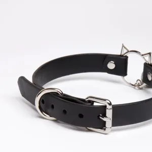 Black leather choker detail shot featuring metal cat ear ring, buckle, and D-ring hardware.