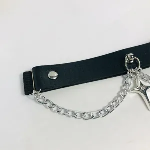 Detail shot of punk gothic Y2K black leather leg garter with silver chain and star pendant.