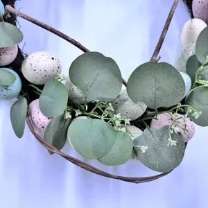 Close-up detail of Easter wreath showing speckled pastel eggs and green eucalyptus leaves